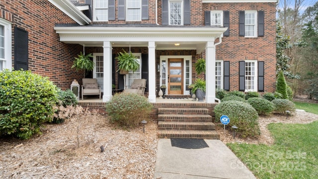 entrance to property with brick siding and covered porch