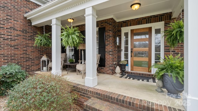 doorway to property featuring brick siding and covered porch