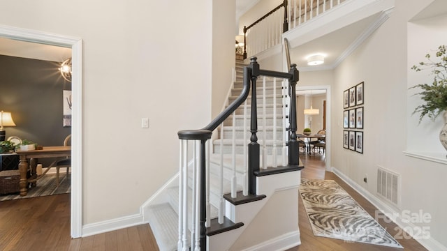 entrance foyer featuring visible vents, crown molding, baseboards, and wood finished floors