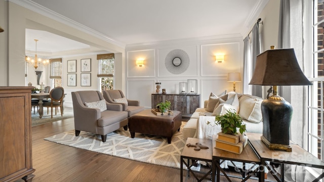 living area featuring a chandelier, a decorative wall, wood finished floors, and ornamental molding