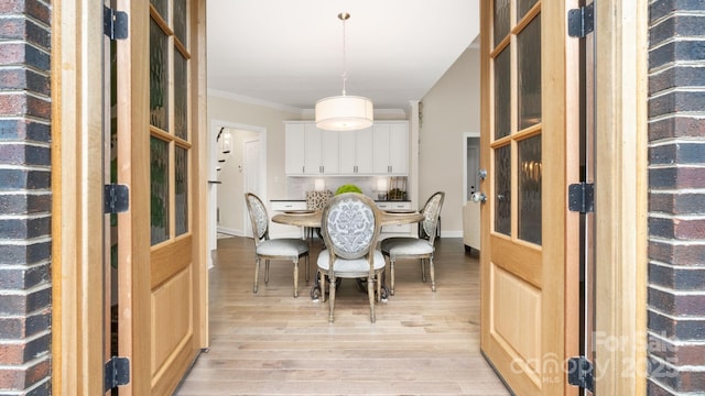 dining area with light wood-type flooring, baseboards, and ornamental molding