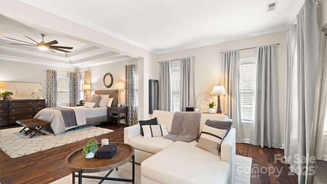 bedroom with visible vents, a tray ceiling, ornamental molding, dark wood-style floors, and a ceiling fan