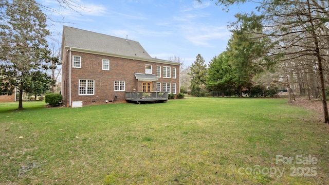 rear view of house featuring a deck, a yard, brick siding, and crawl space