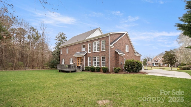 rear view of property featuring brick siding, a deck, and a yard