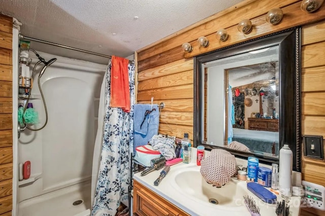 bathroom with a textured ceiling, log walls, a shower stall, and vanity