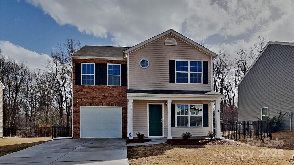 traditional home featuring brick siding, an attached garage, concrete driveway, and fence