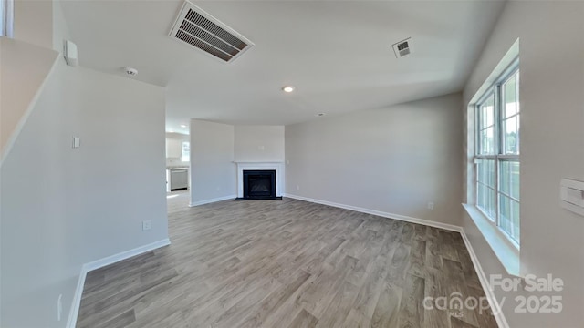 unfurnished living room with visible vents, a fireplace with flush hearth, and wood finished floors