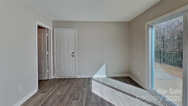 spare room featuring baseboards and dark wood-style flooring