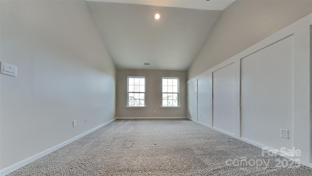 spare room featuring visible vents, baseboards, lofted ceiling, and carpet