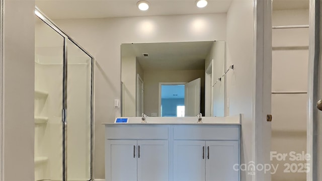 full bathroom with double vanity, a shower stall, and a sink