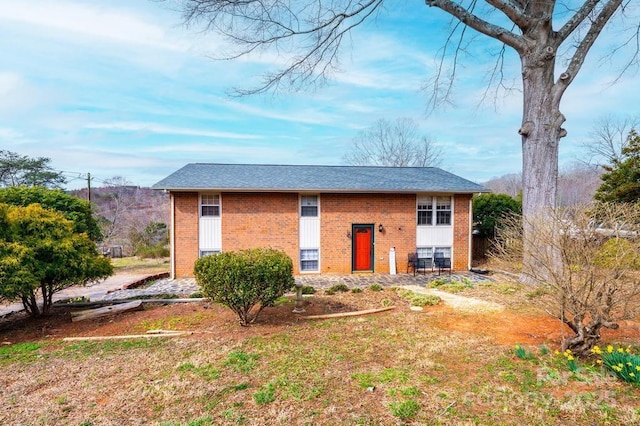 view of front of house with roof with shingles and brick siding