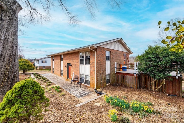 rear view of property with a patio, brick siding, and fence