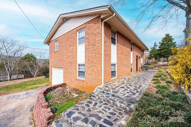 view of side of property featuring brick siding and an attached garage