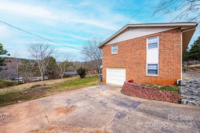 view of side of home featuring an attached garage, concrete driveway, and brick siding