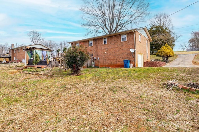 back of house featuring a garage, a yard, and brick siding