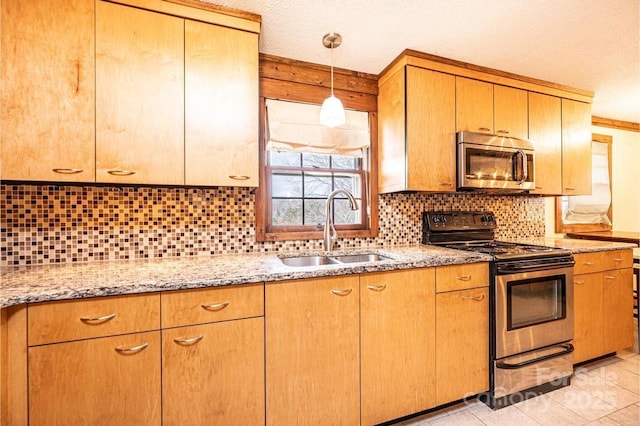 kitchen featuring light stone counters, pendant lighting, decorative backsplash, appliances with stainless steel finishes, and a sink