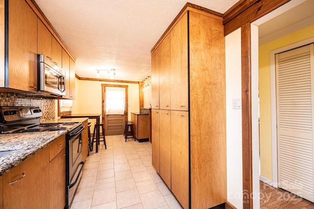 kitchen featuring electric stove, tasteful backsplash, stainless steel microwave, and brown cabinets