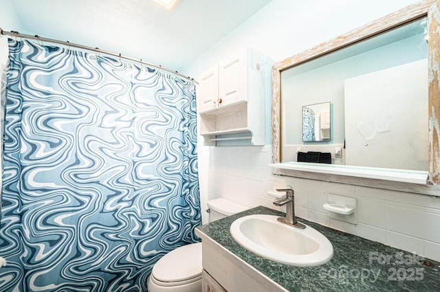 full bathroom with vanity, toilet, and tile walls