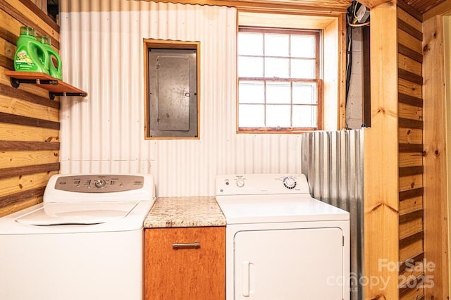 washroom featuring wooden walls, separate washer and dryer, cabinet space, and electric panel