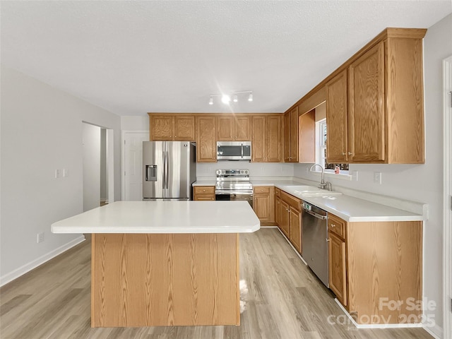 kitchen with stainless steel appliances, light wood-type flooring, a sink, and a kitchen island