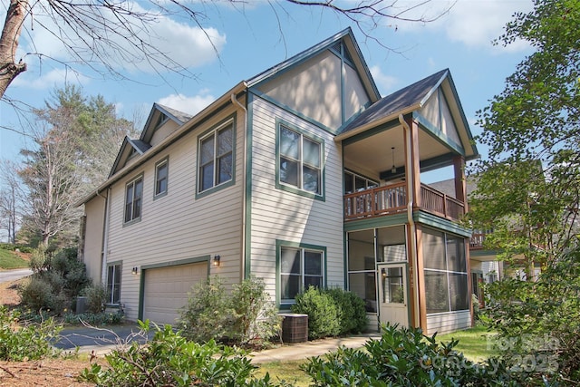 view of side of home with central air condition unit, an attached garage, a sunroom, and a balcony