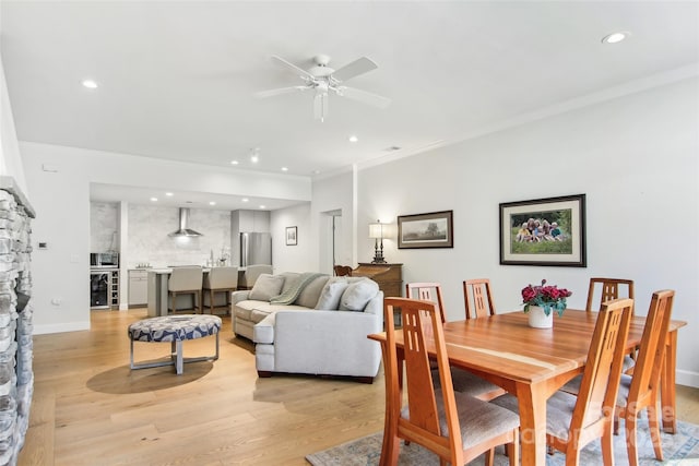 dining space with light wood-style flooring, recessed lighting, a ceiling fan, crown molding, and beverage cooler