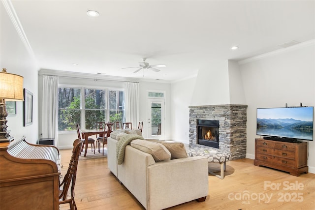 living area featuring ceiling fan, crown molding, light wood finished floors, and a fireplace