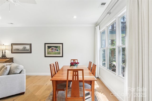 dining room featuring light wood finished floors, a healthy amount of sunlight, and crown molding