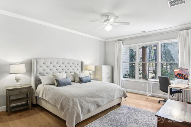 bedroom featuring wood finished floors, visible vents, crown molding, and baseboards