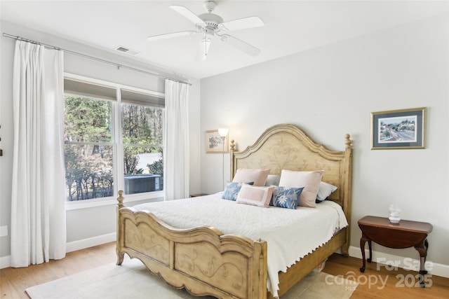 bedroom with baseboards, wood finished floors, multiple windows, and visible vents