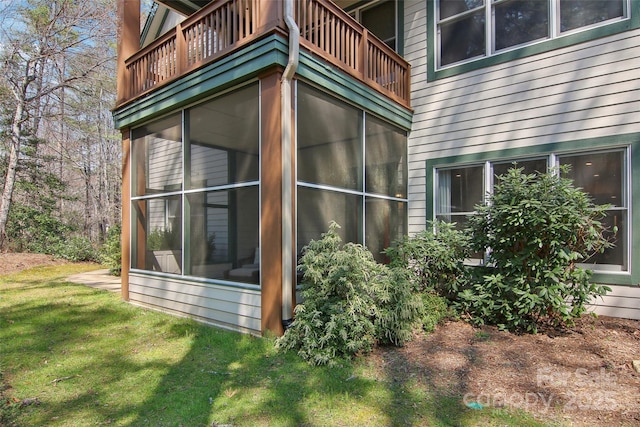 view of home's exterior with a sunroom, a balcony, and a yard