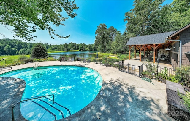 pool featuring fence, a patio, and a water view