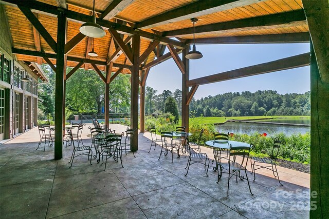 view of patio with outdoor dining area, a view of trees, and a water view