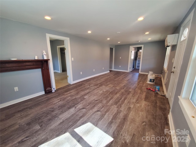 unfurnished living room with recessed lighting, baseboards, dark wood-type flooring, and a wall mounted AC