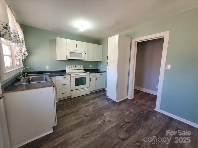 kitchen with dark countertops, white cabinets, white appliances, and a sink