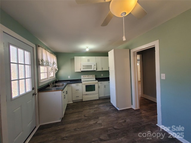 kitchen with white appliances, a sink, dark wood-type flooring, white cabinets, and dark countertops