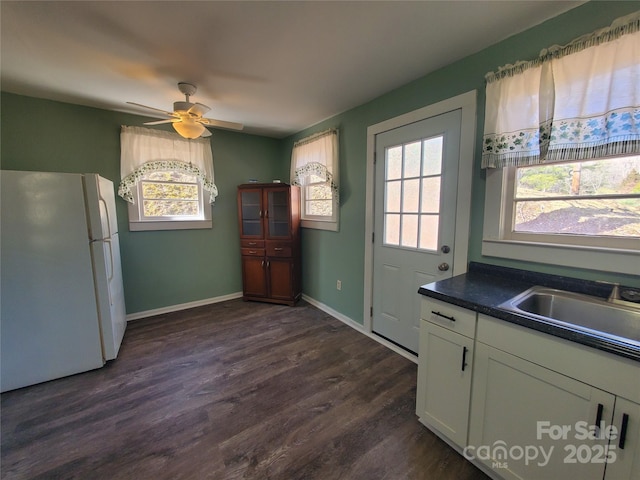 kitchen with a sink, a healthy amount of sunlight, dark wood-style floors, and freestanding refrigerator