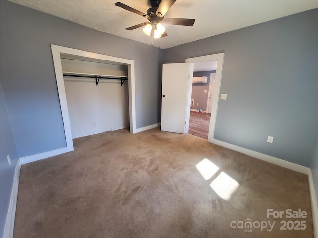 unfurnished bedroom featuring a ceiling fan, a wall unit AC, a closet, carpet, and baseboards