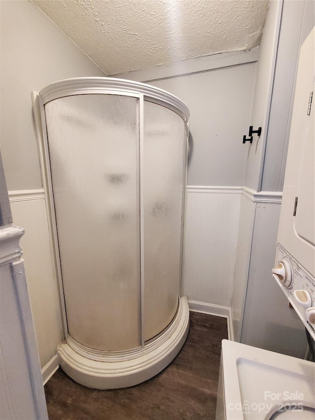 full bathroom featuring a shower stall, wood finished floors, and a textured ceiling