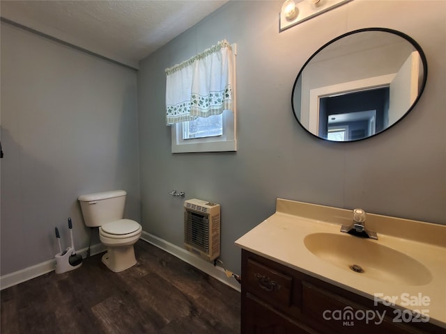 half bath featuring vanity, wood finished floors, baseboards, a textured ceiling, and toilet