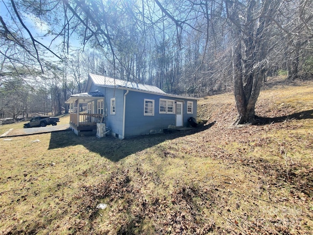 view of side of property featuring metal roof, a lawn, and concrete block siding