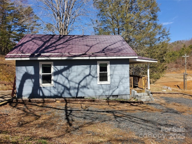 view of home's exterior with metal roof and crawl space