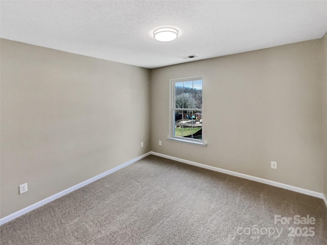 carpeted spare room with visible vents, a textured ceiling, and baseboards