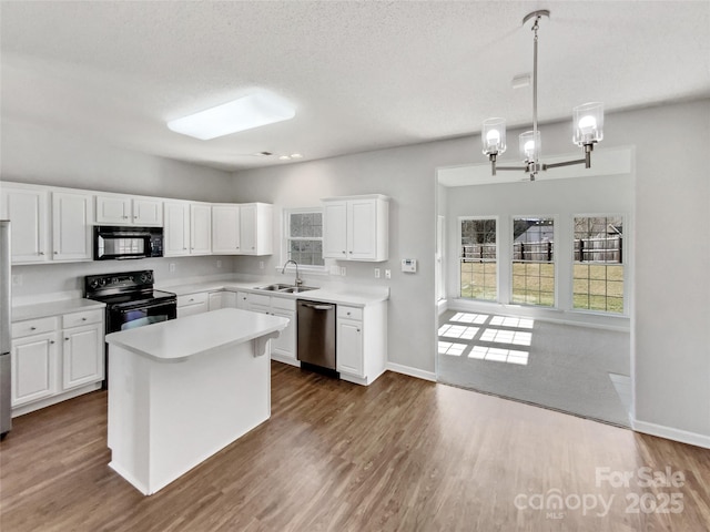 kitchen featuring dark wood-type flooring, light countertops, black appliances, white cabinetry, and a sink