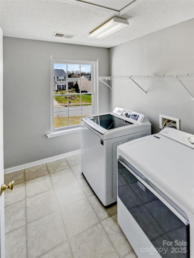 laundry room featuring laundry area, baseboards, visible vents, washing machine and clothes dryer, and a textured ceiling