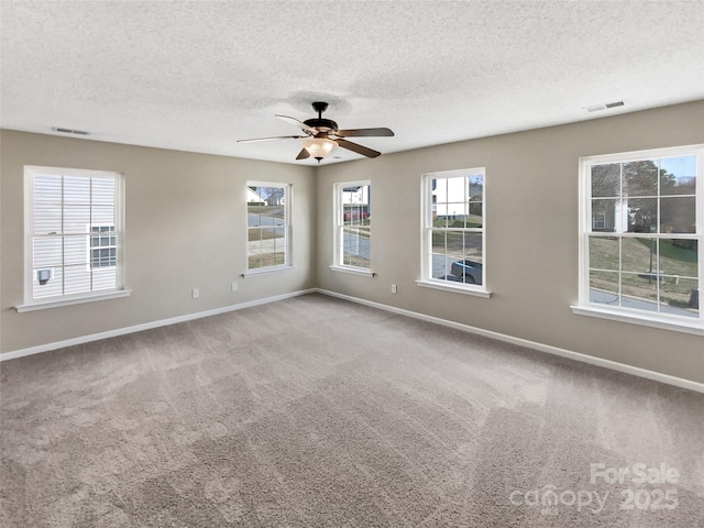 carpeted spare room featuring visible vents, ceiling fan, and baseboards