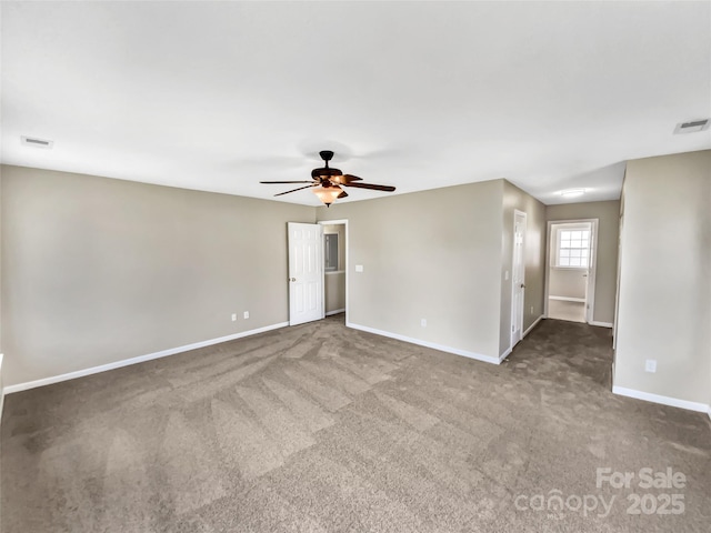 carpeted spare room featuring ceiling fan, visible vents, and baseboards