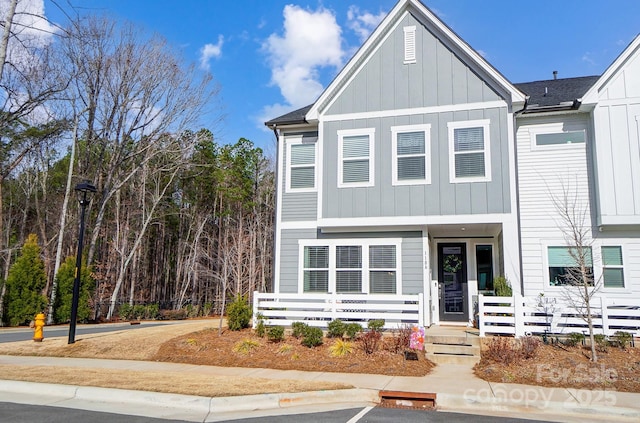 townhome / multi-family property featuring board and batten siding, roof with shingles, and fence