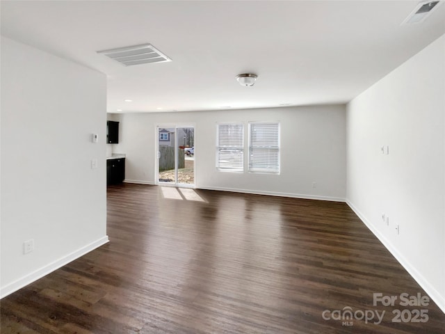 unfurnished living room with dark wood-style floors, baseboards, and visible vents