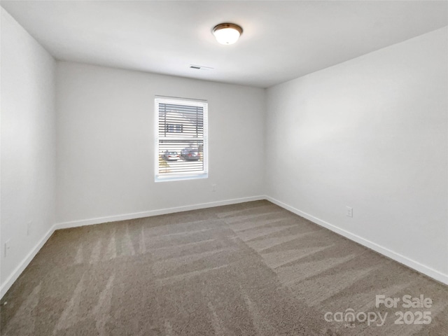 unfurnished room with carpet floors, visible vents, and baseboards